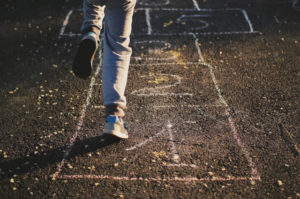 a cropped photo of a child playing hopscotch, with only the legs visible