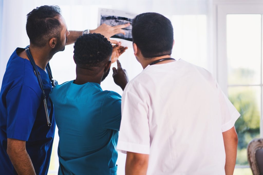 Three medical providers examining an x-ray
